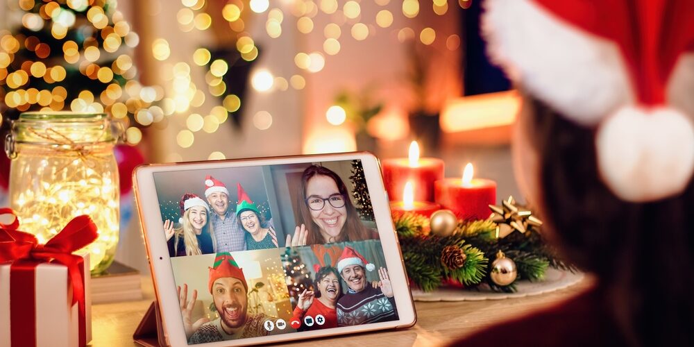 Young woman having a Christmas video call with her happy family. Concept of families in quarantine during Christmas because of the coronavirus. Xmas still life with a tablet in a cozy room
